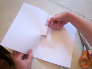 Step 2: Open paper and poke finger into the cut section in the center of the paper and gently pull forward to make a stair step.